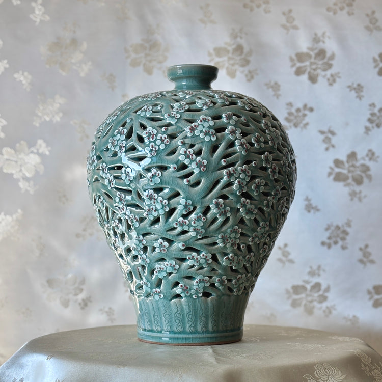 Handmade Korean celadon double-wall openwork vase featuring intricate plum blossom motifs in white and red, showcasing traditional craftsmanship.