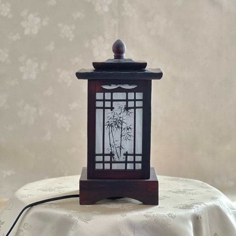 Front view of a handmade Korean traditional wooden table lamp with a square pagoda-shaped roof and Sagunja patterns.