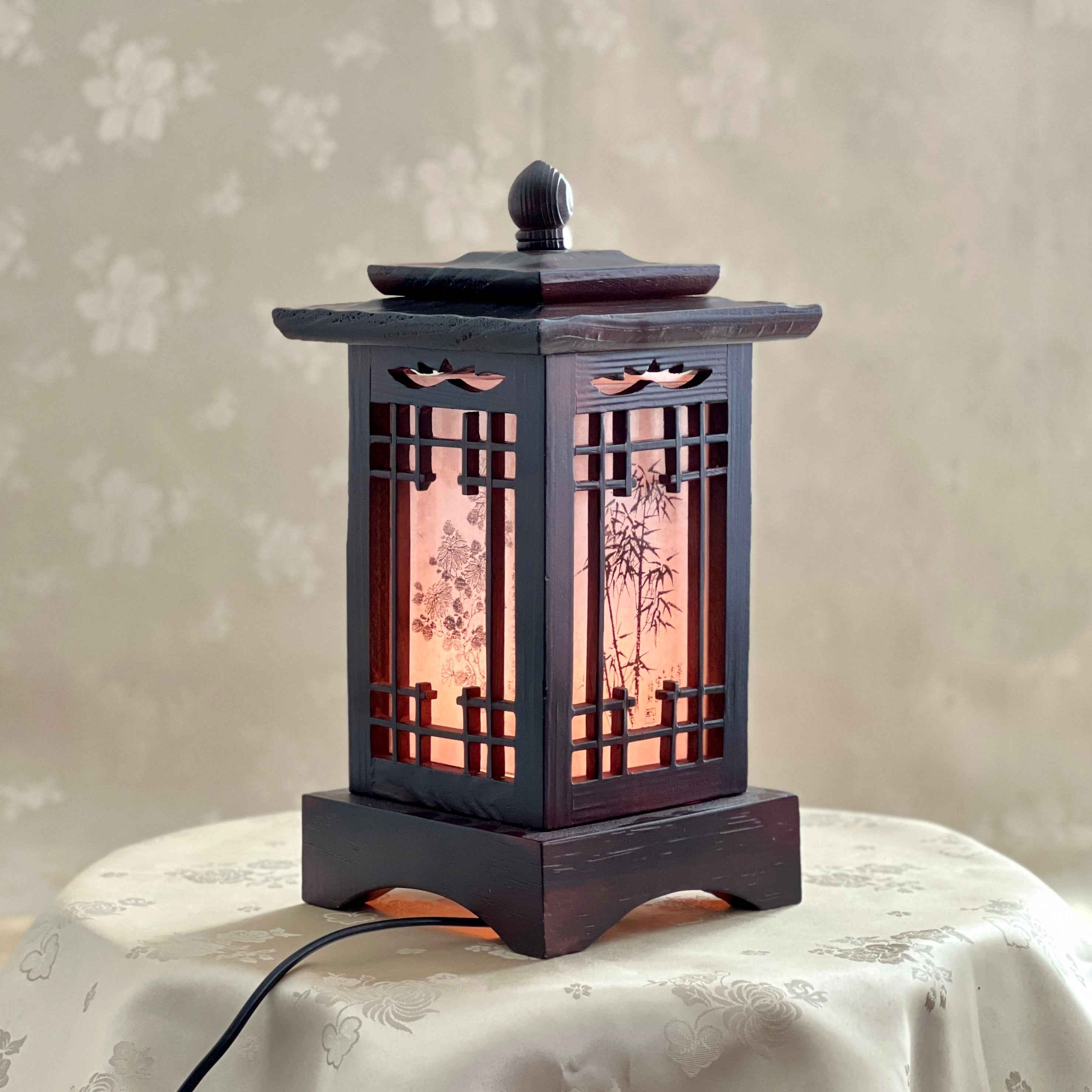 Front view of a handmade Korean traditional wooden table lamp with a square pagoda-shaped roof and Sagunja patterns.