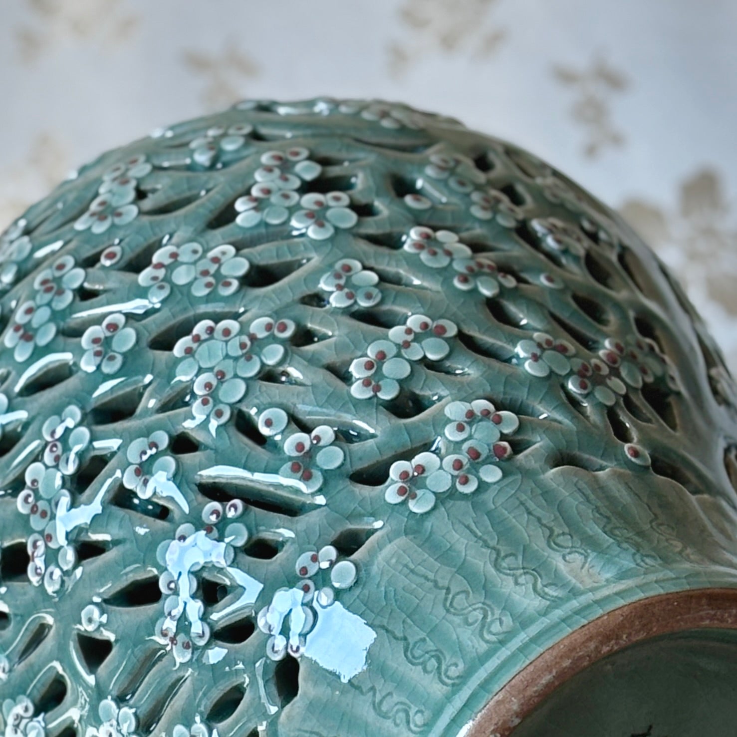 Handmade Korean celadon double-wall openwork vase featuring intricate plum blossom motifs in white and red, showcasing traditional craftsmanship.