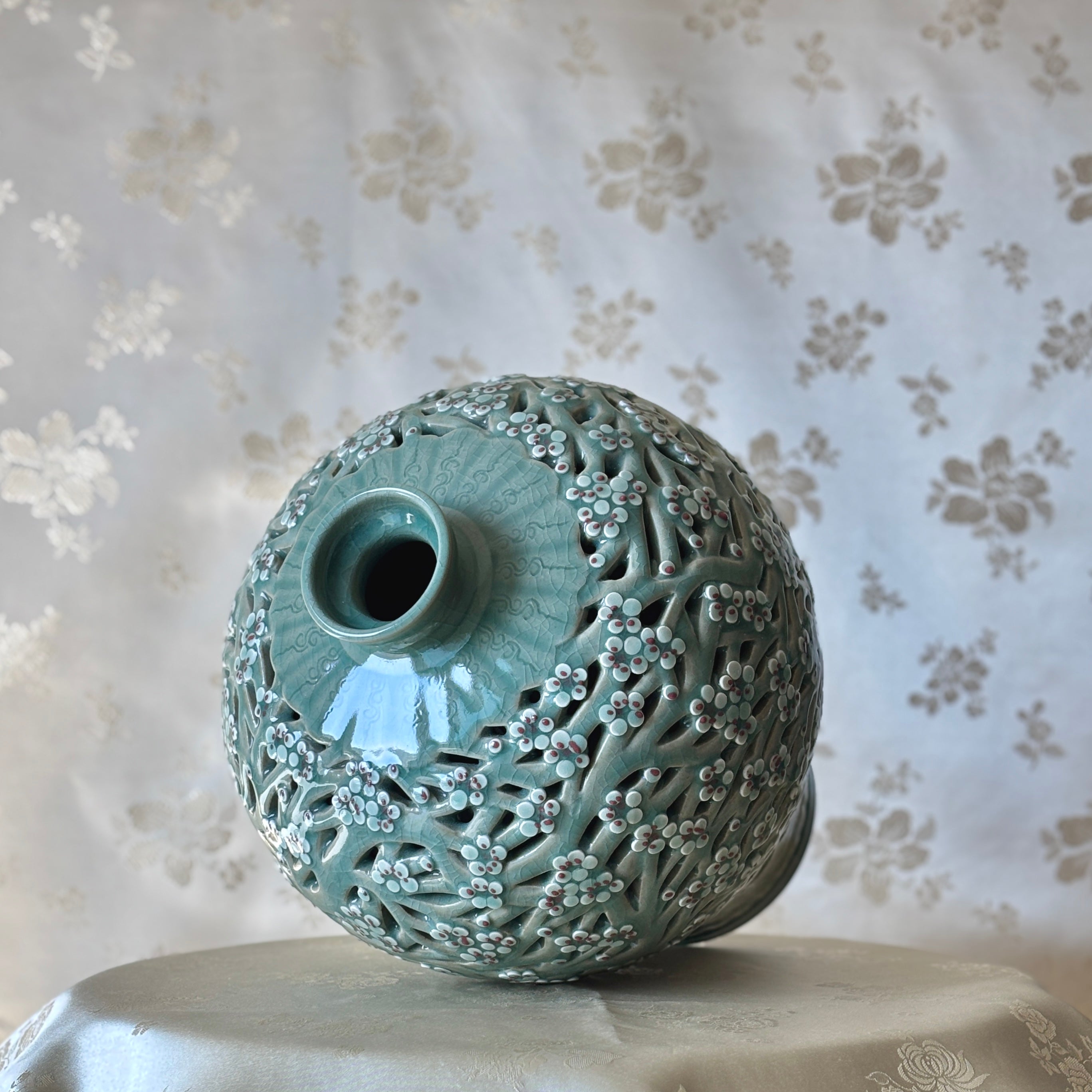 Handmade Korean celadon double-wall openwork vase featuring intricate plum blossom motifs in white and red, showcasing traditional craftsmanship.