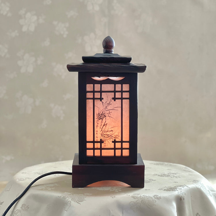 Front view of a handmade Korean traditional wooden table lamp with a square pagoda-shaped roof and Sagunja patterns.