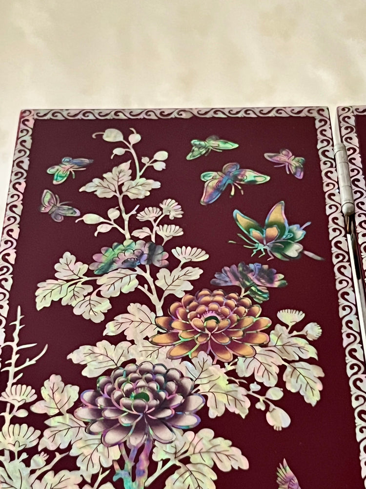 Korean Traditional Handmade Mother of Pearl Black Color Wooden Folding Screen on a table, featuring a pattern of birds, butterflies, and flowers.